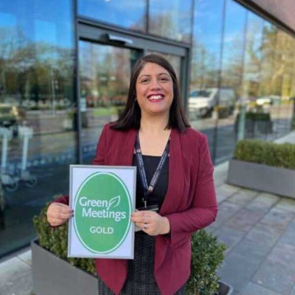 A smiling woman in business attire holding a Green Tourism award